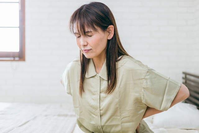 腰に手を当て腰痛に悩む女性
